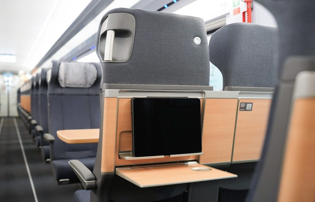 The back of one of the seats in the new interior with a tablet placed in a designated holder behind the chair's fold out table